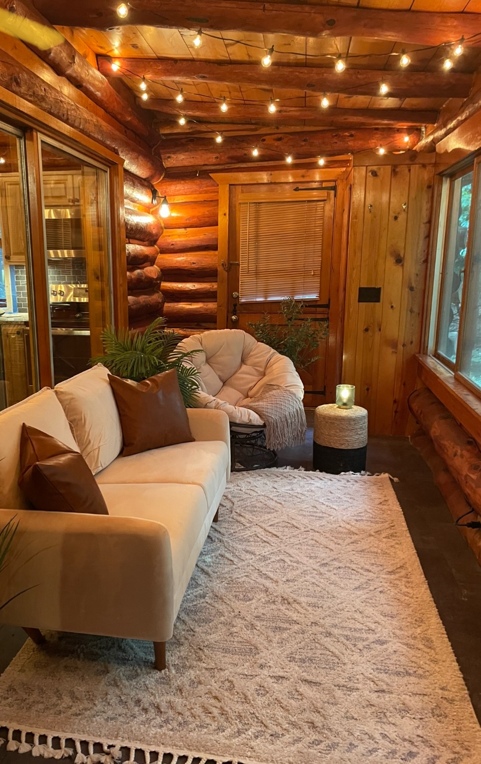 Four‑season sunroom with sofa and string lights